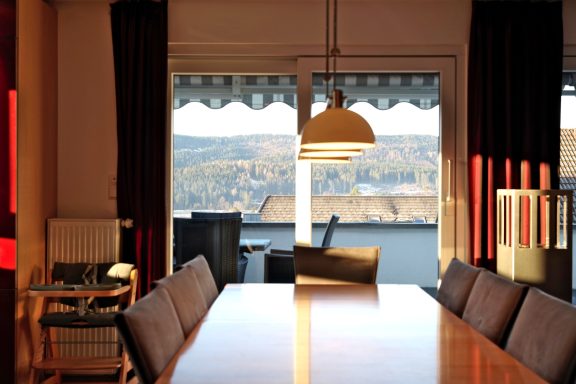 Esszimmer mit Blick auf eine Landschaft und einem großen Fenster, warmes Licht.