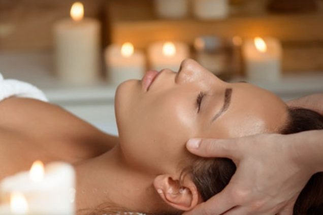 Frau erhält entspannten Massage mit Kerzenlicht im Hintergrund.