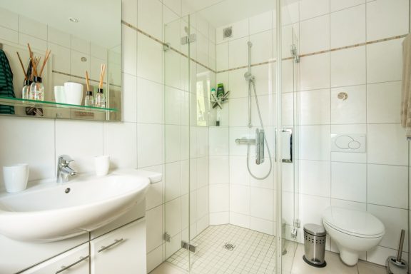 Helles Badezimmer mit Dusche, Waschbecken und modernen Armaturen.