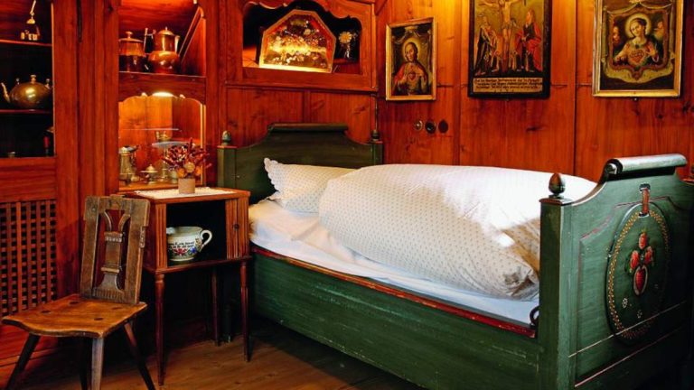 Holzvertäfeltes Zimmer mit einem Bett, dekorativem Nachttisch und nostalgischem Ambiente.