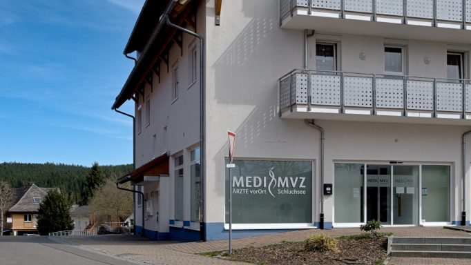Eingang zu einem modernen Gebäude mit großen Fenstern und einem ruhigen Umfeld.
