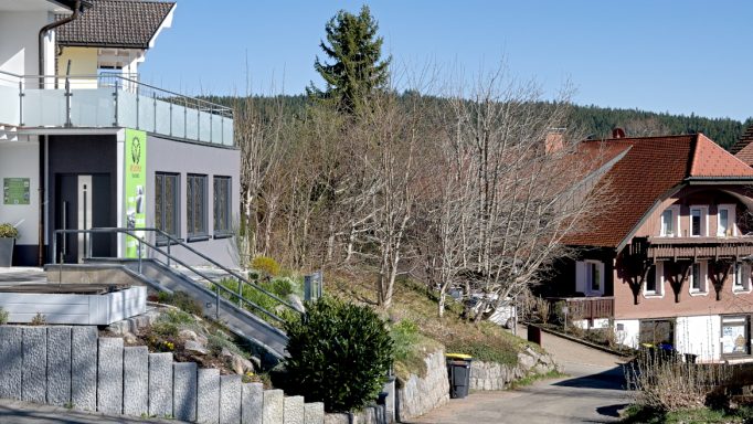 Links die Geschäftsräume von MYEASYWAY in einem zweistöckigen Haus mit Treppenzugang und Garten. Im Hintergrund ein Schwarzwald-Haus.