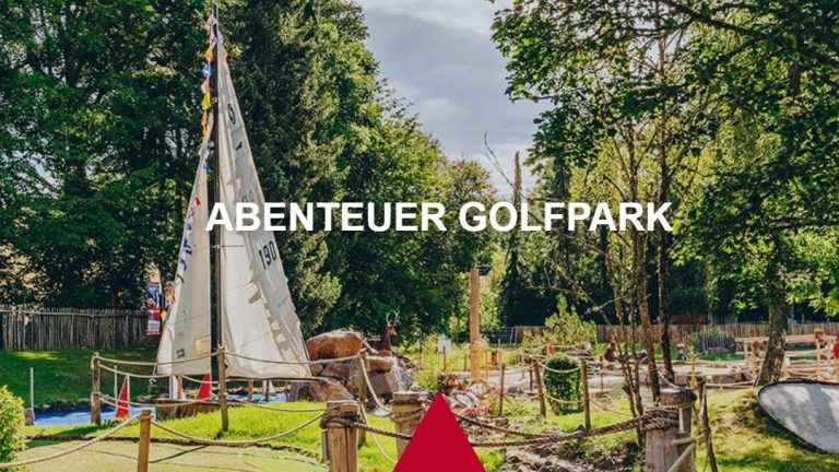 Ein Teil des Abenteuer Golfplatzes mit einem Bootssegel, Holzpflöcken, die mit Seilen verbunden sind und vielen Bäumen.