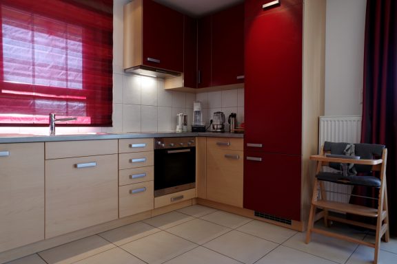 Moderne Küche mit roten Akzenten, Holzschränken und Geräten.