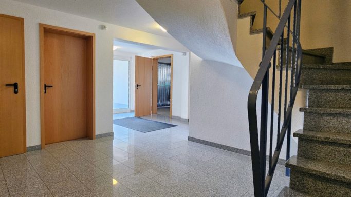 Heller Flur mit Türen und Treppe, modernes Design, viel natürlichem Licht.