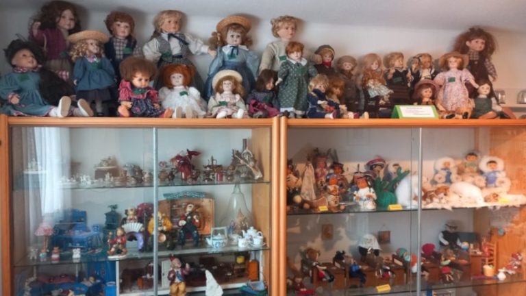 Vitrine mit vielen verschiedenen Puppen und Spielzeugfiguren.